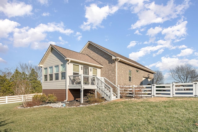 rear view of property featuring a wooden deck and a yard