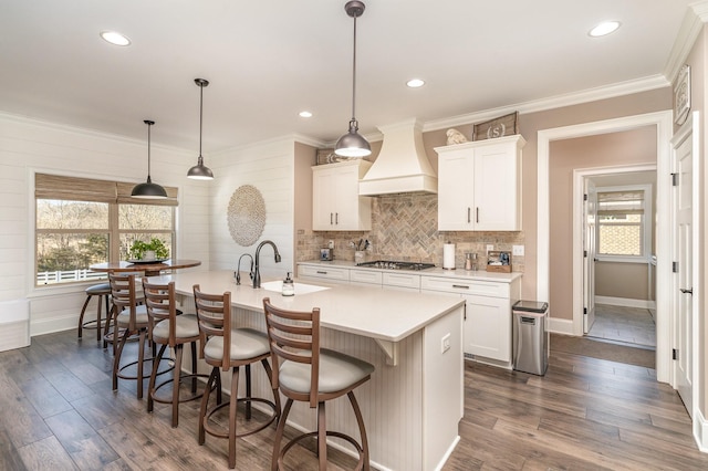 kitchen featuring premium range hood, sink, white cabinetry, hanging light fixtures, and stainless steel gas stovetop