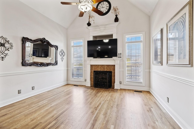 unfurnished living room with a tiled fireplace, lofted ceiling, and a wealth of natural light