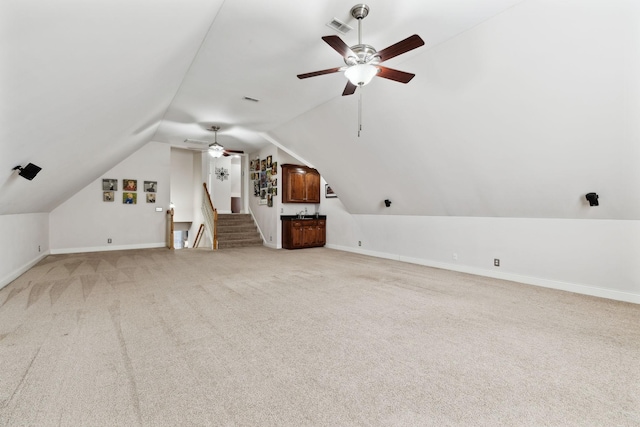 additional living space featuring ceiling fan, vaulted ceiling, and light carpet