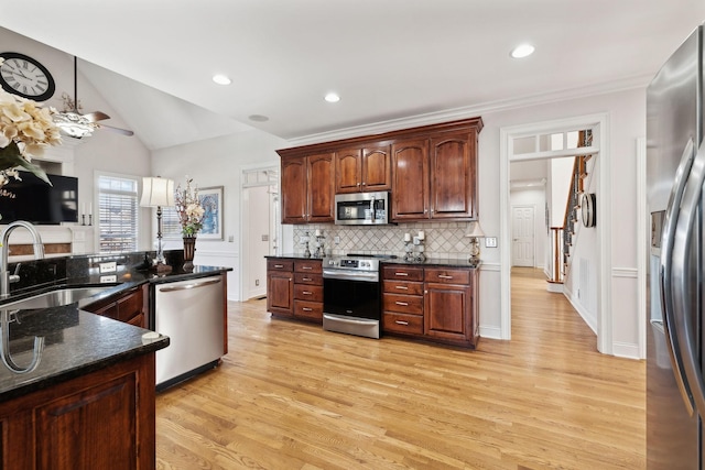 kitchen featuring sink, light hardwood / wood-style flooring, stainless steel appliances, tasteful backsplash, and dark stone counters