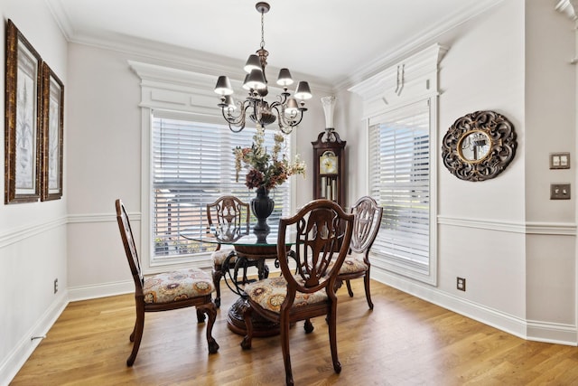 dining space with light hardwood / wood-style flooring, crown molding, plenty of natural light, and a chandelier