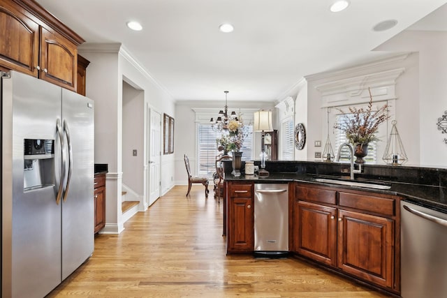 kitchen featuring sink, crown molding, hanging light fixtures, light wood-type flooring, and appliances with stainless steel finishes