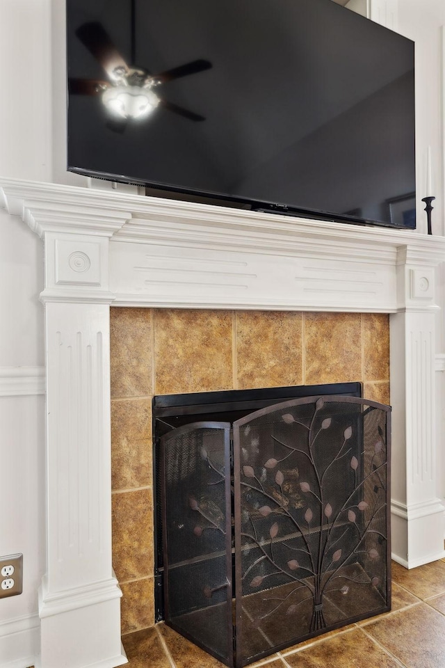 interior details with ceiling fan and a tiled fireplace