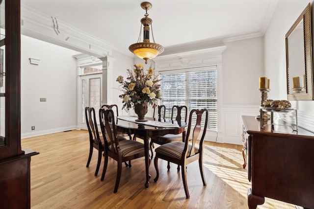 dining room with crown molding, light hardwood / wood-style flooring, and ornate columns