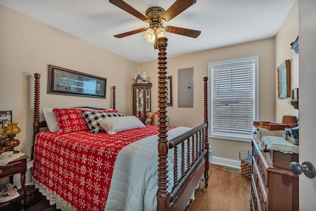 bedroom with hardwood / wood-style floors, electric panel, and ceiling fan