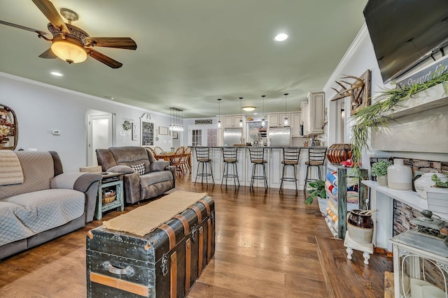 living room featuring wood-type flooring, ornamental molding, and ceiling fan