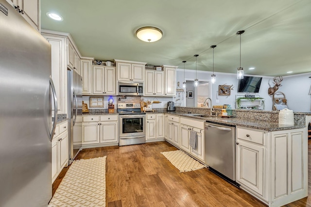 kitchen with sink, decorative light fixtures, stainless steel appliances, and kitchen peninsula