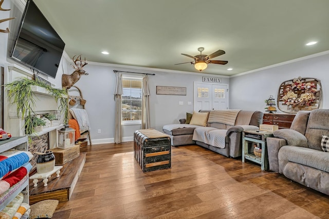 living room featuring wood-type flooring, ornamental molding, and ceiling fan