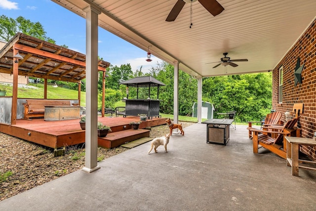 view of patio / terrace with a storage shed, ceiling fan, a deck, a gazebo, and a hot tub