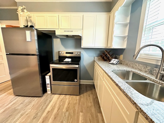 kitchen with light hardwood / wood-style floors, appliances with stainless steel finishes, light stone countertops, and sink