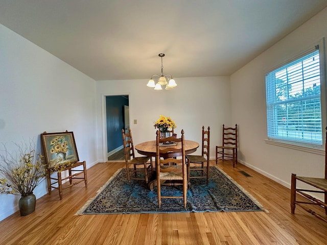 dining room with light hardwood / wood-style flooring and a chandelier