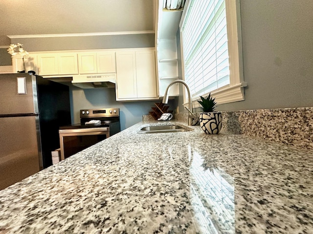 kitchen with light stone counters, appliances with stainless steel finishes, sink, and white cabinets