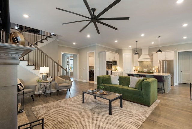 living room featuring ceiling fan, ornamental molding, and light wood-type flooring