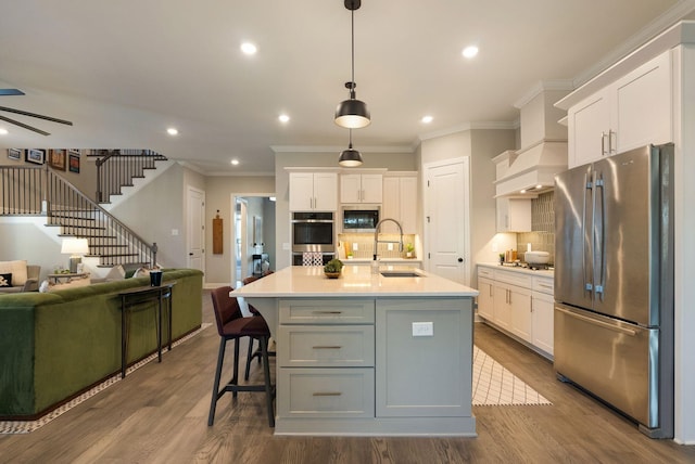 kitchen featuring white cabinetry, stainless steel appliances, sink, and a kitchen island with sink