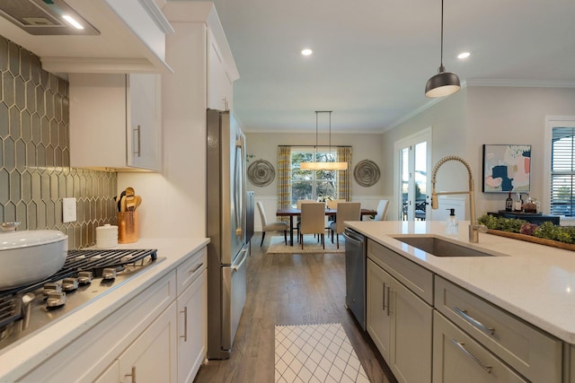 kitchen with sink, white cabinets, hanging light fixtures, stainless steel appliances, and custom range hood