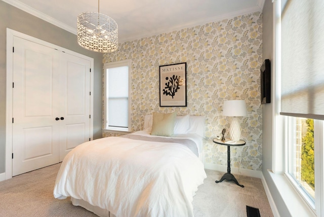 carpeted bedroom with an inviting chandelier, a closet, ornamental molding, and multiple windows