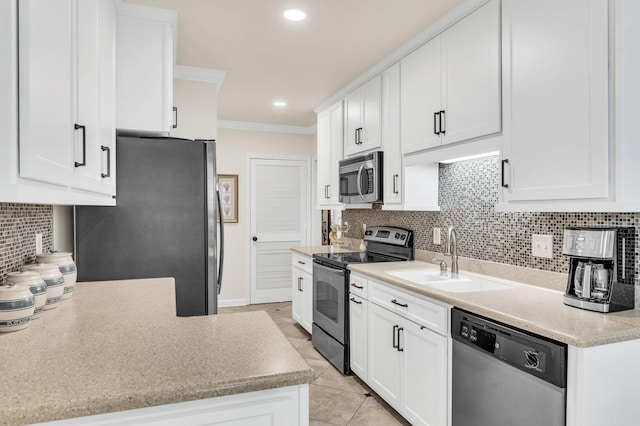 kitchen featuring appliances with stainless steel finishes, tasteful backsplash, sink, white cabinets, and ornamental molding