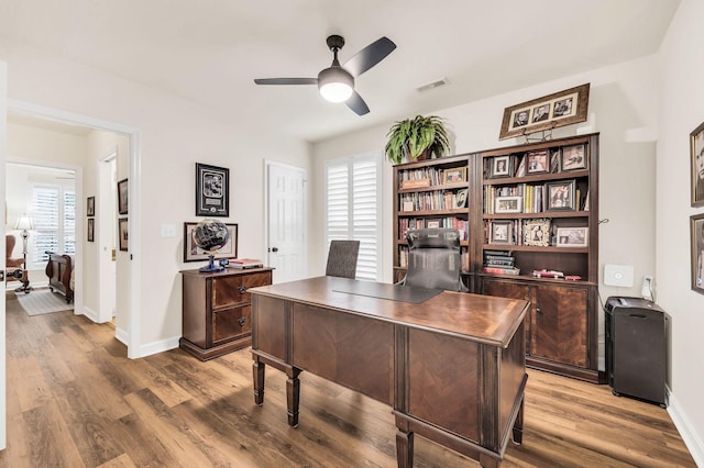 home office with hardwood / wood-style flooring and ceiling fan