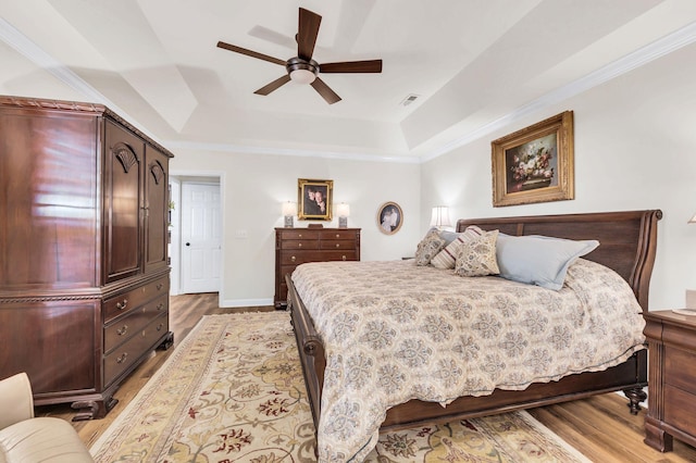 bedroom featuring a tray ceiling, ornamental molding, and light hardwood / wood-style floors