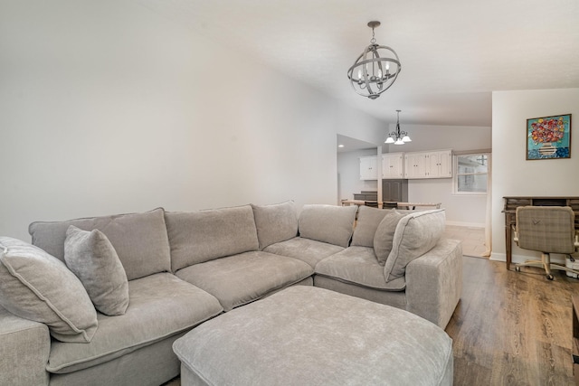 living room with an inviting chandelier, wood-type flooring, and vaulted ceiling