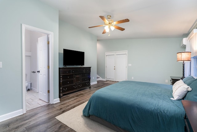 bedroom featuring vaulted ceiling, a wall mounted air conditioner, hardwood / wood-style floors, ceiling fan, and ensuite bath