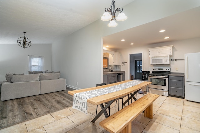 tiled dining room featuring lofted ceiling, a chandelier, and sink