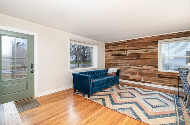 sitting room with wood walls, ornamental molding, and light wood-type flooring