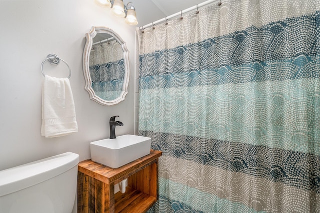 bathroom with a shower with shower curtain, toilet, and sink