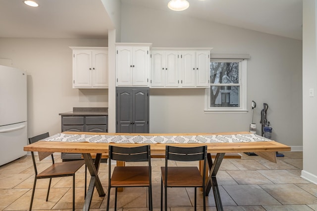 kitchen featuring white refrigerator, vaulted ceiling, and white cabinets