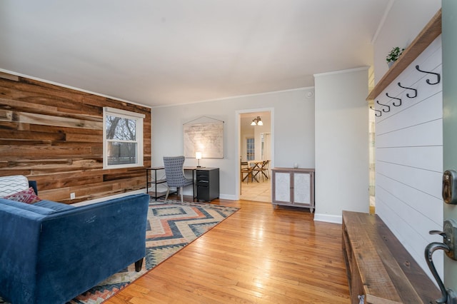 living room featuring ornamental molding, wooden walls, and light hardwood / wood-style floors