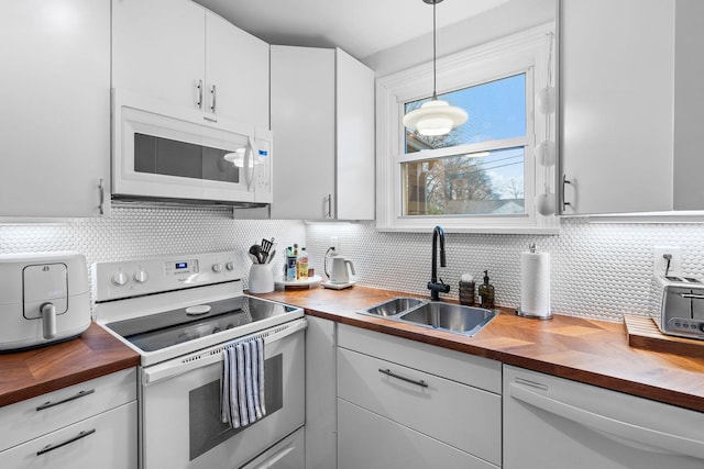 kitchen with pendant lighting, butcher block counters, sink, and white appliances