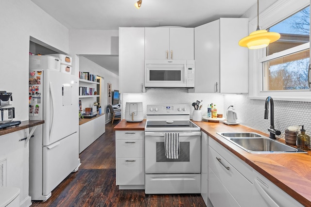 kitchen featuring white appliances, wooden counters, decorative light fixtures, and white cabinets