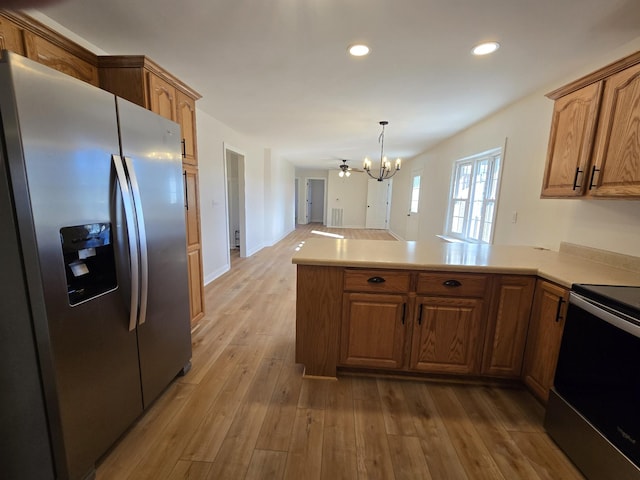 kitchen with appliances with stainless steel finishes, decorative light fixtures, a notable chandelier, light hardwood / wood-style floors, and kitchen peninsula