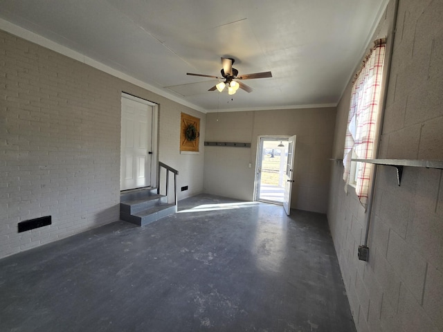 unfurnished room featuring ceiling fan and brick wall