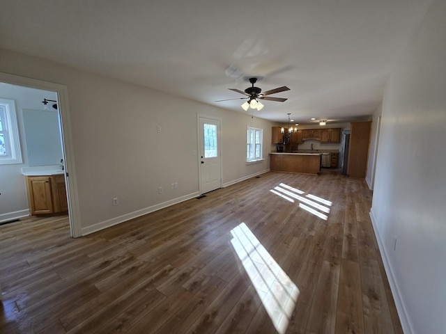 unfurnished living room with dark hardwood / wood-style flooring and ceiling fan