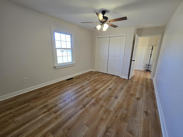 unfurnished bedroom with ceiling fan, wood-type flooring, and a closet