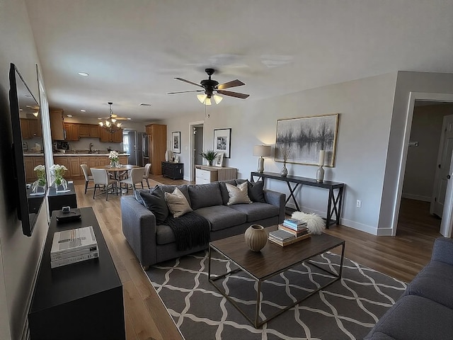 living room featuring sink, ceiling fan with notable chandelier, and light hardwood / wood-style flooring