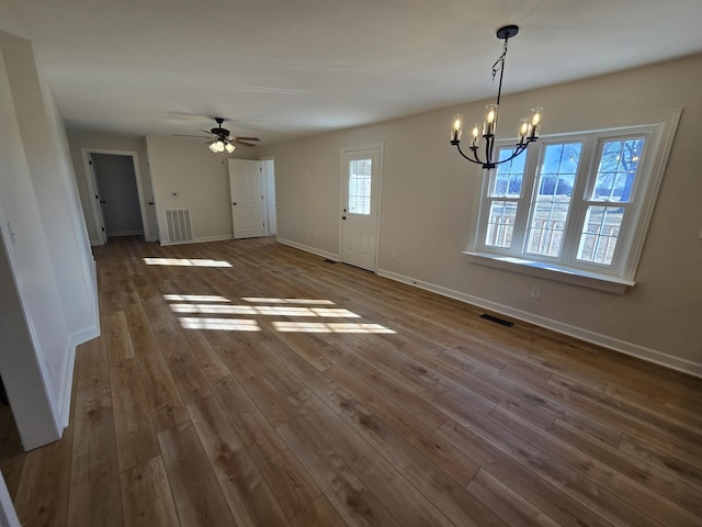 unfurnished dining area featuring ceiling fan with notable chandelier and dark hardwood / wood-style floors