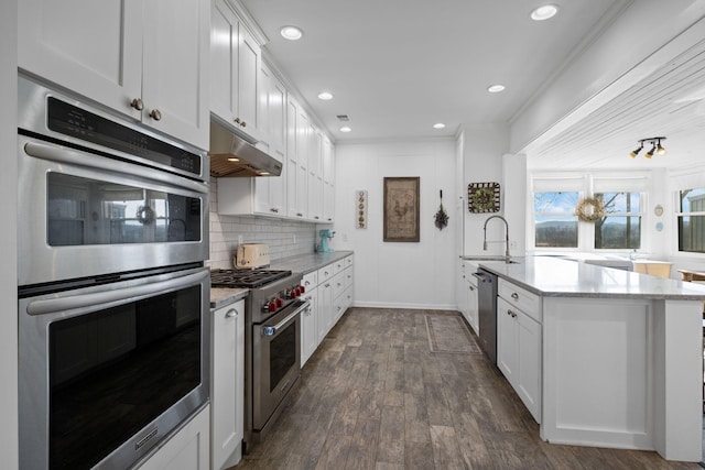 kitchen featuring sink, stainless steel appliances, tasteful backsplash, light stone countertops, and white cabinets