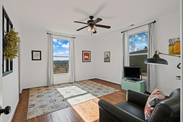 living room featuring ceiling fan, dark wood-type flooring, and a healthy amount of sunlight