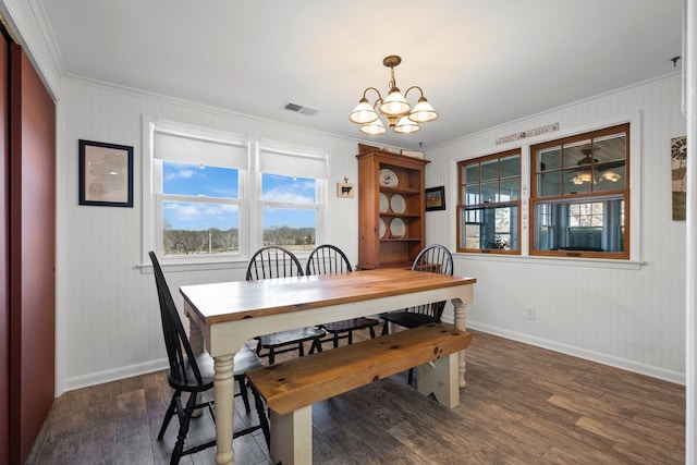 dining area with a wealth of natural light, an inviting chandelier, and dark hardwood / wood-style flooring