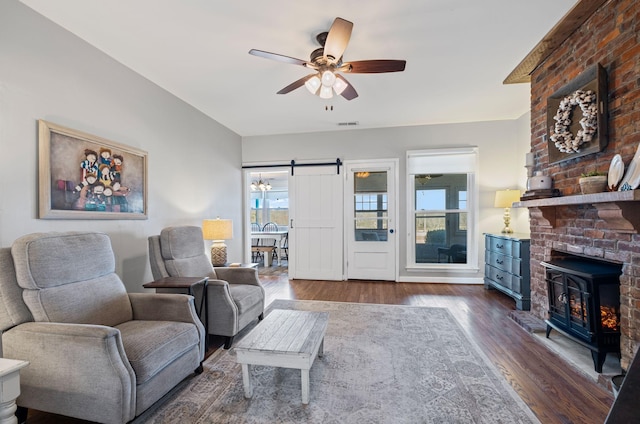 living room featuring ceiling fan, a barn door, and dark hardwood / wood-style flooring