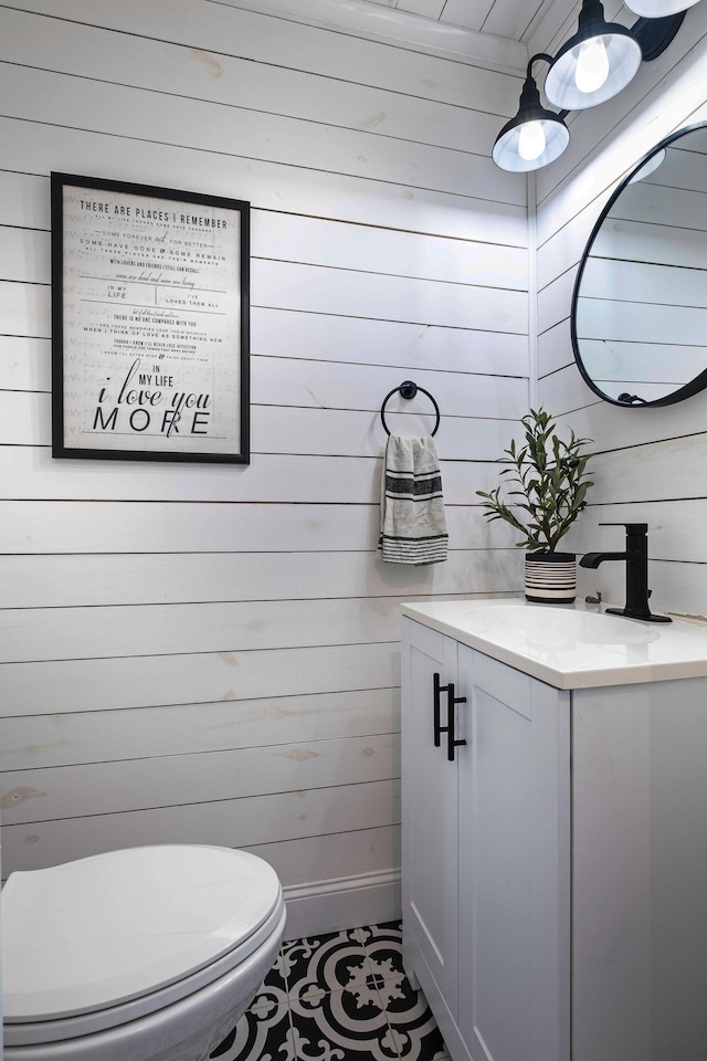 bathroom featuring wooden walls, tile patterned floors, vanity, and toilet