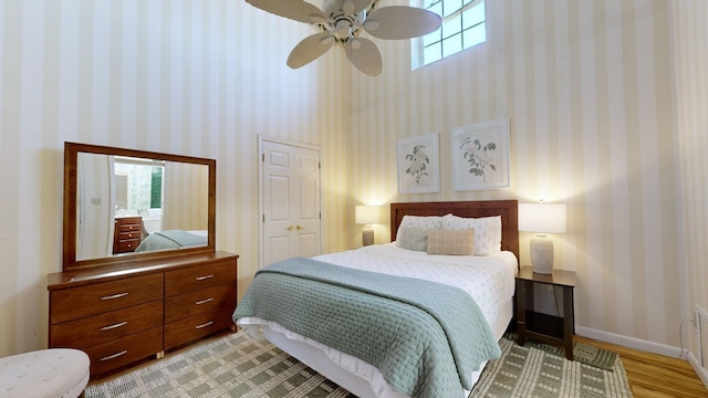 bedroom featuring hardwood / wood-style flooring, ceiling fan, and a towering ceiling