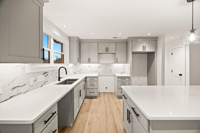 kitchen featuring hanging light fixtures, gray cabinets, sink, and a center island