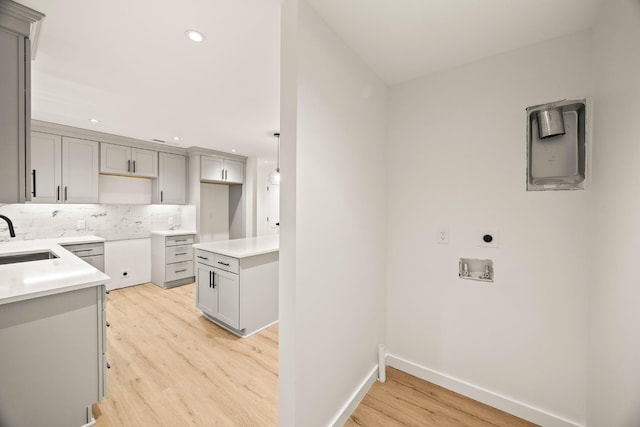 kitchen with tasteful backsplash, sink, gray cabinets, and light hardwood / wood-style floors