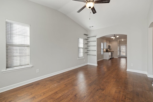 unfurnished living room with lofted ceiling, dark wood-type flooring, and ceiling fan with notable chandelier