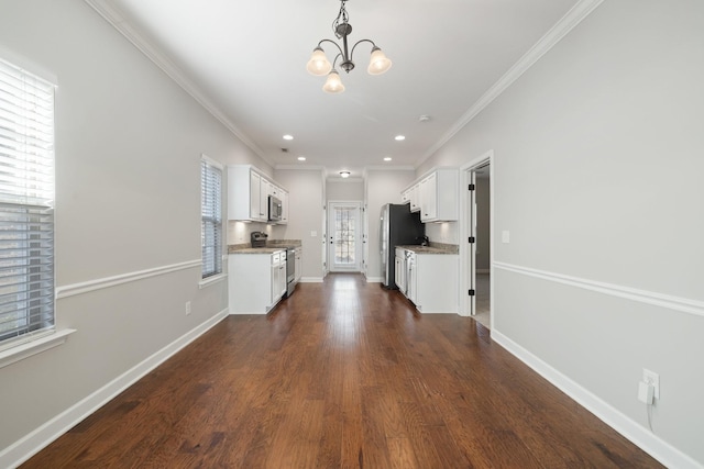 kitchen with pendant lighting, dark wood-type flooring, stainless steel appliances, ornamental molding, and white cabinets