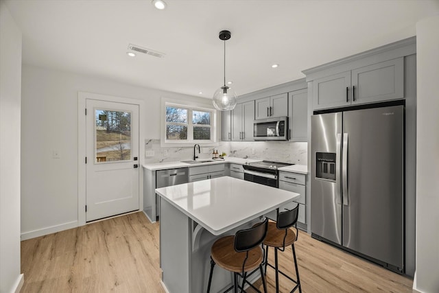 kitchen featuring a kitchen island, appliances with stainless steel finishes, pendant lighting, tasteful backsplash, and sink